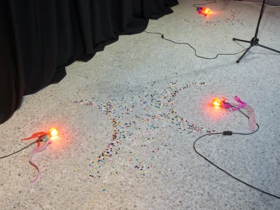 Johanna Odersky, 
Untitled, 2023,
Mikrofonständer, Glühbirnen, Seidenpapier, 
Kabel, Konfetti, Vorhänge